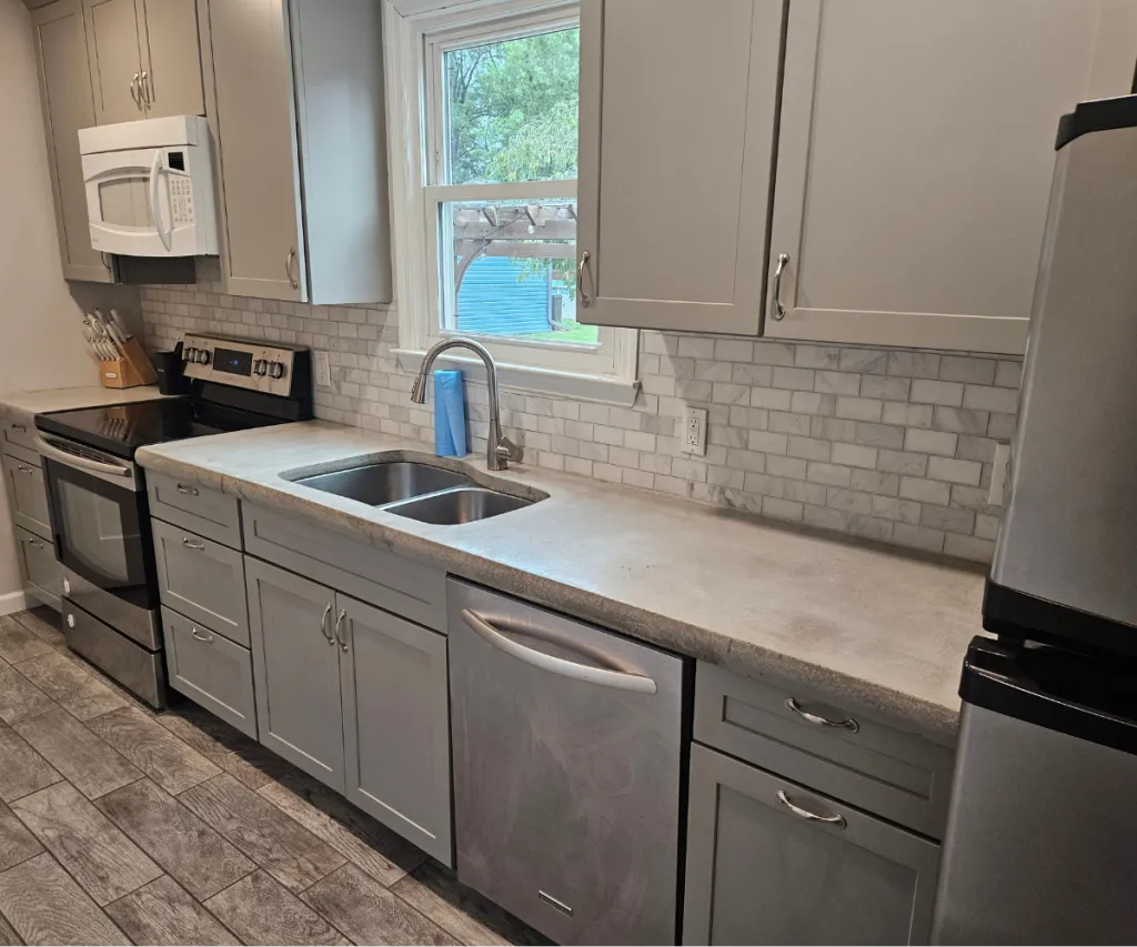 Gray kitchen with a double sink, dishwasher and marble subway backsplash