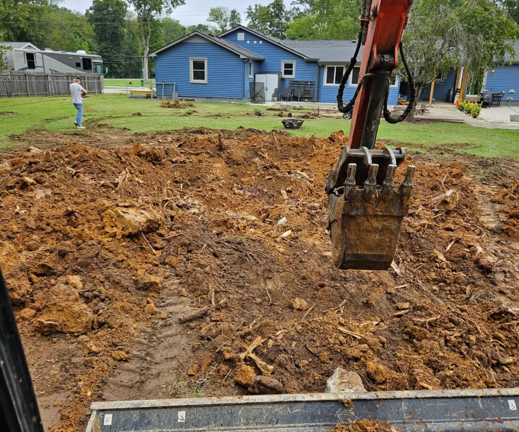 Mini excavator digging a trench across a backyard lawn