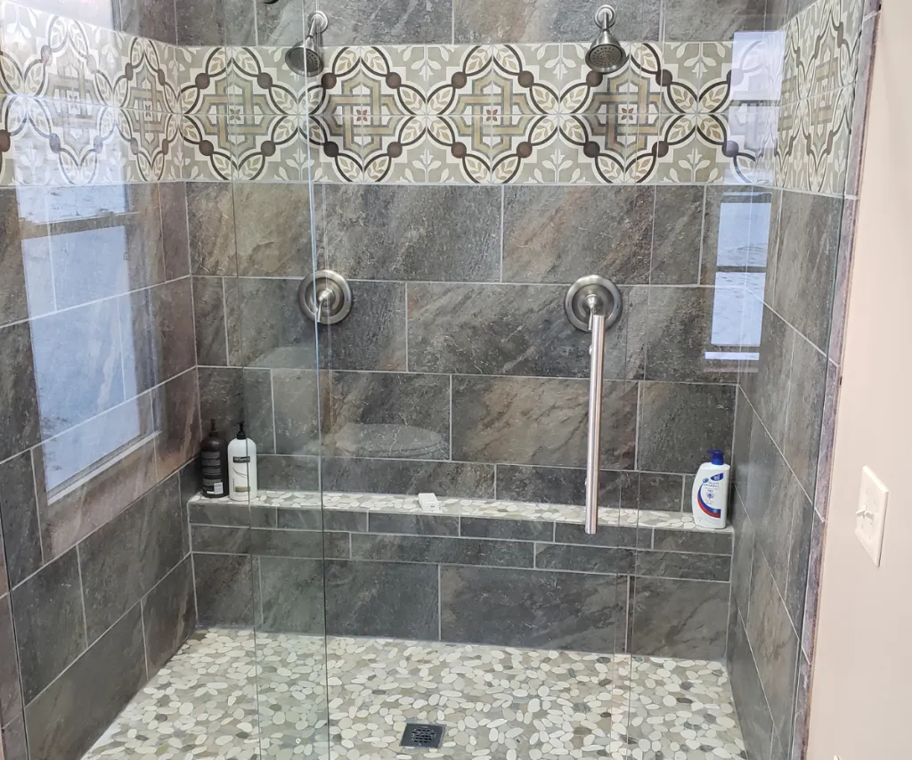 Tiled walk-in shower with a patterned border band and a pebble floor